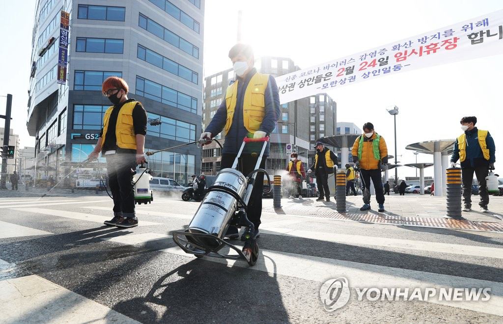 為了防止新冠肺炎擴散，京畿道城南市牡丹市場24日停業一天。防疫人員正在對市場地面進行消毒作業。