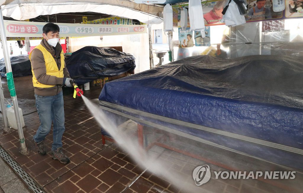 為了防止新冠肺炎擴散，京畿道城南市牡丹市場24日停業一天。防疫人員正在對市場進行消毒作業。