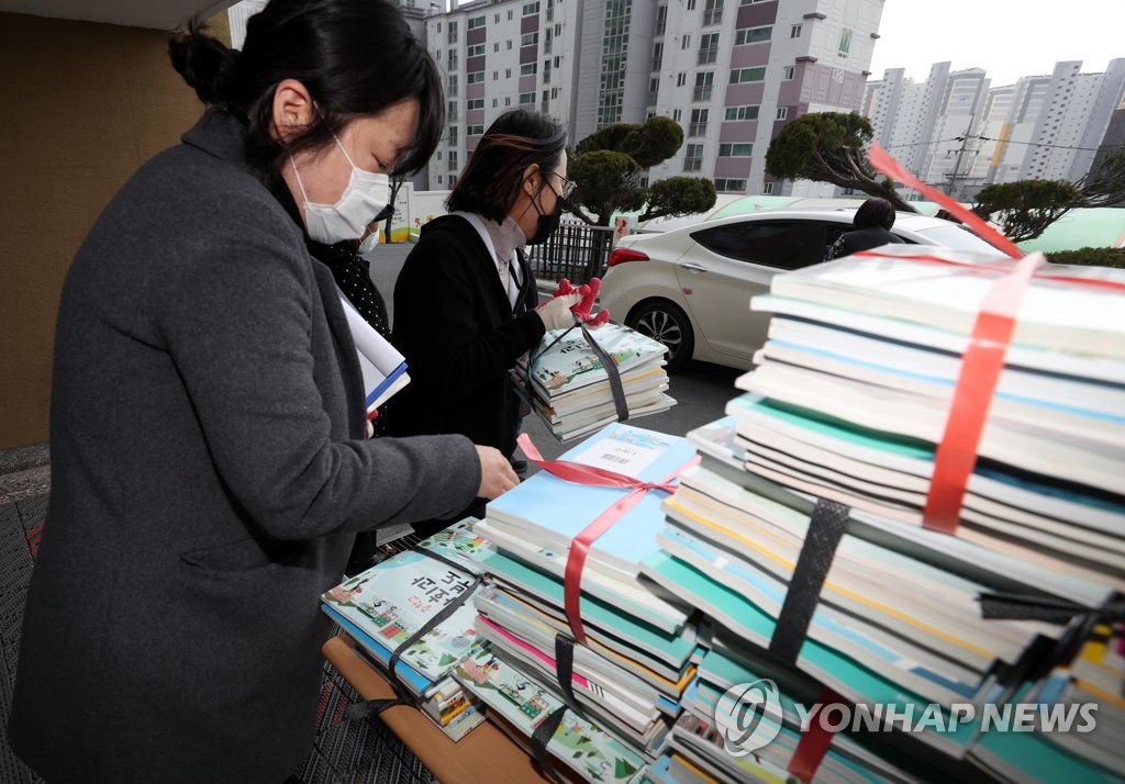 19日，在慶北永川市永川中學，班主任將新學期教科書轉交給車內的學生家長。