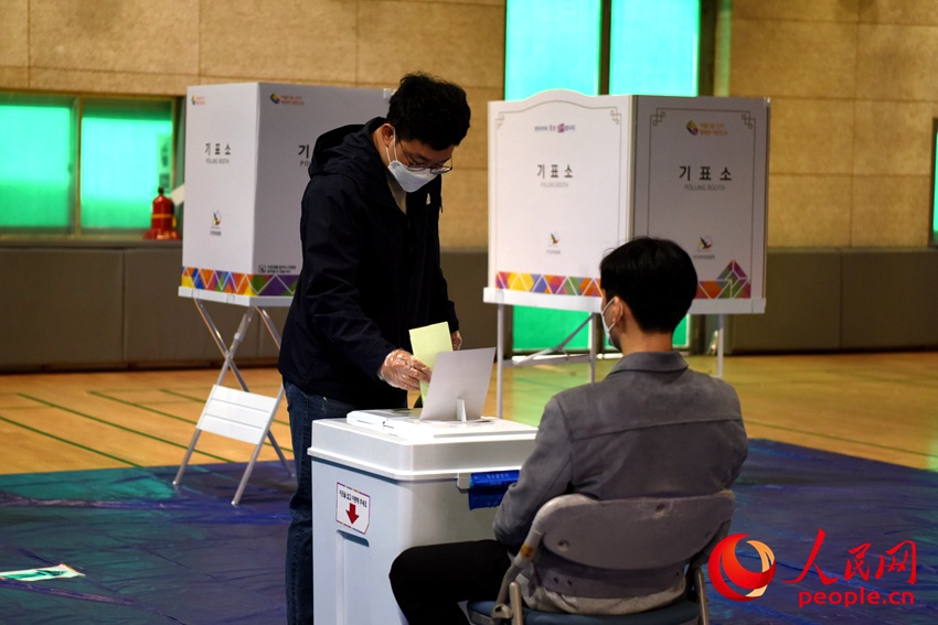 選民戴上一次性手套進行投票。裴埈基攝