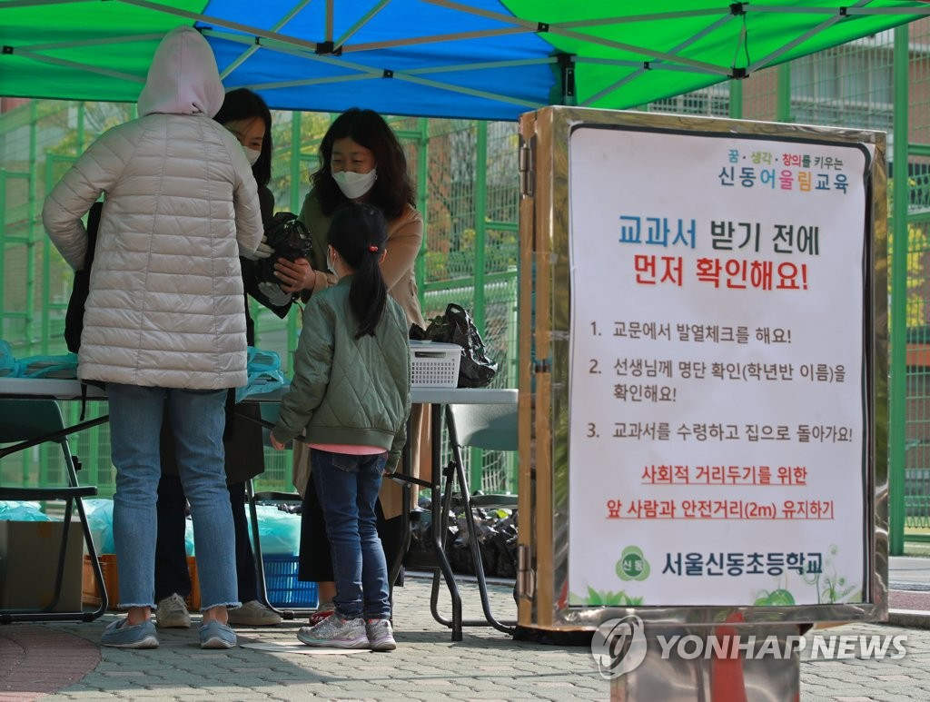 16日，首爾新東小學門口，在校學生和家長正在領取教材。