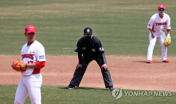 4月9日，在光州起亞冠軍棒球場，司壘裁判員（黑衣）戴口罩進行比賽。 圖源：韓聯社