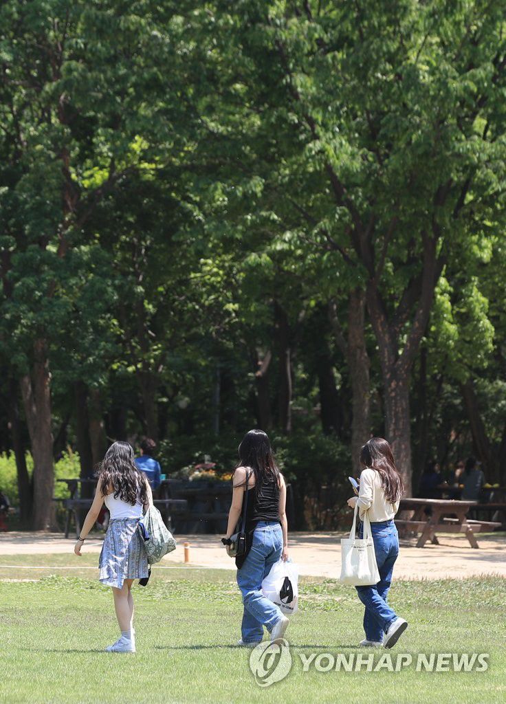  5月6日，在“首爾林”公園，三位女性友人並肩走在草坪上。