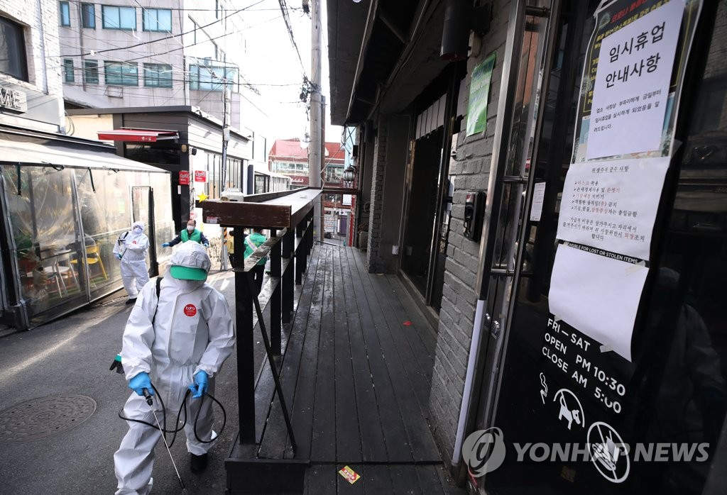 在首爾龍山區牛師團路一帶的夜店周圍，防疫志願者們正在進行噴洒消毒。