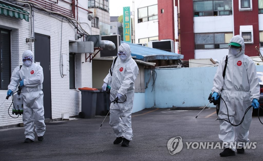 在首爾龍山區牛師團路King夜店附近街道上，防疫志願者們正在進行消毒作業。