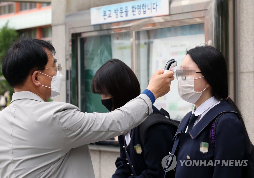 20日上午，在首爾某高中，學生在進入教室前接受體溫檢測。