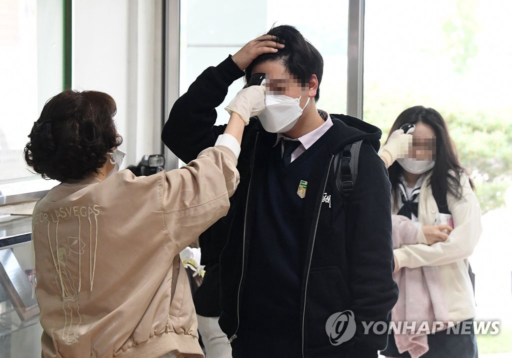20日上午，在首爾某高中，學生在進入教室前接受體溫檢測。