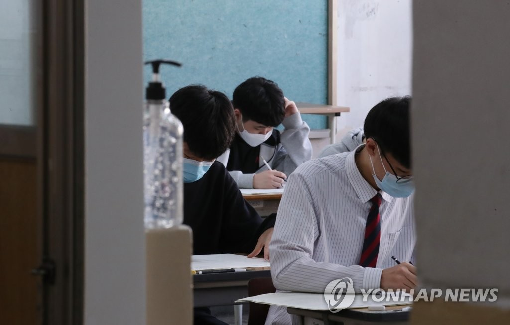 在首爾永登浦區汝矣島高中，學生們在考前確認考卷，並在答題紙上填寫個人信息。