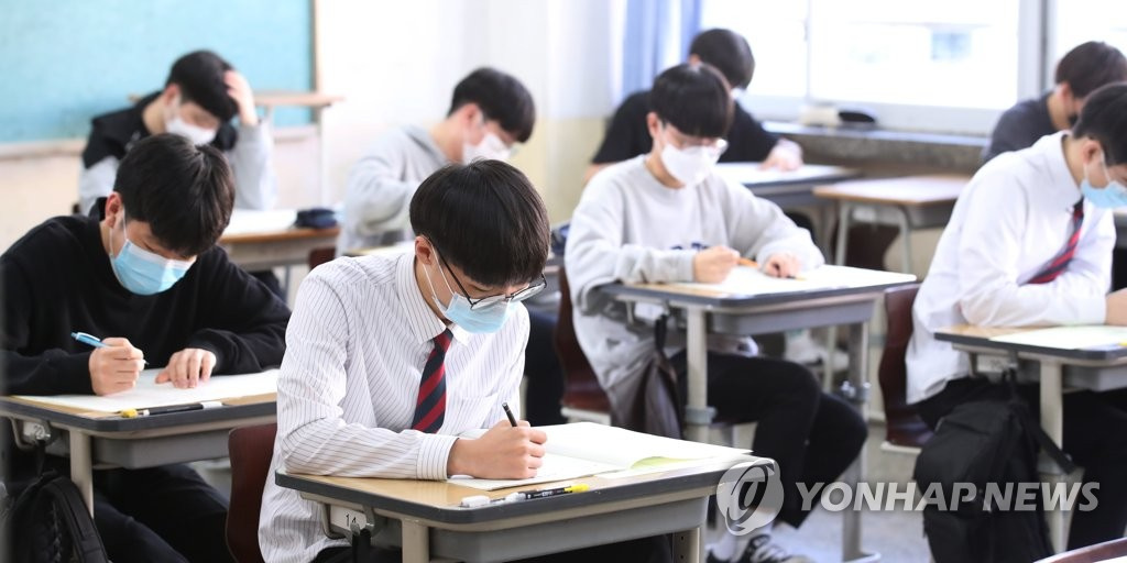 在首爾永登浦區汝矣島高中，學生們在考前確認考卷，並在答題紙上填寫個人信息。