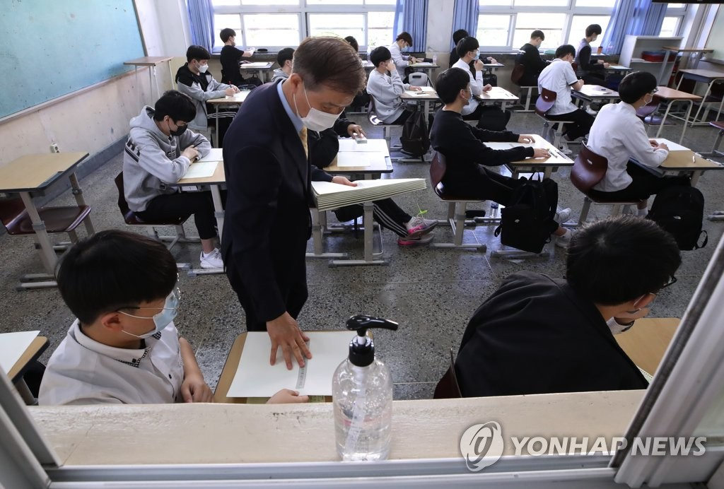 在首爾永登浦區汝矣島高中，老師為同學分發答題卡和試卷。