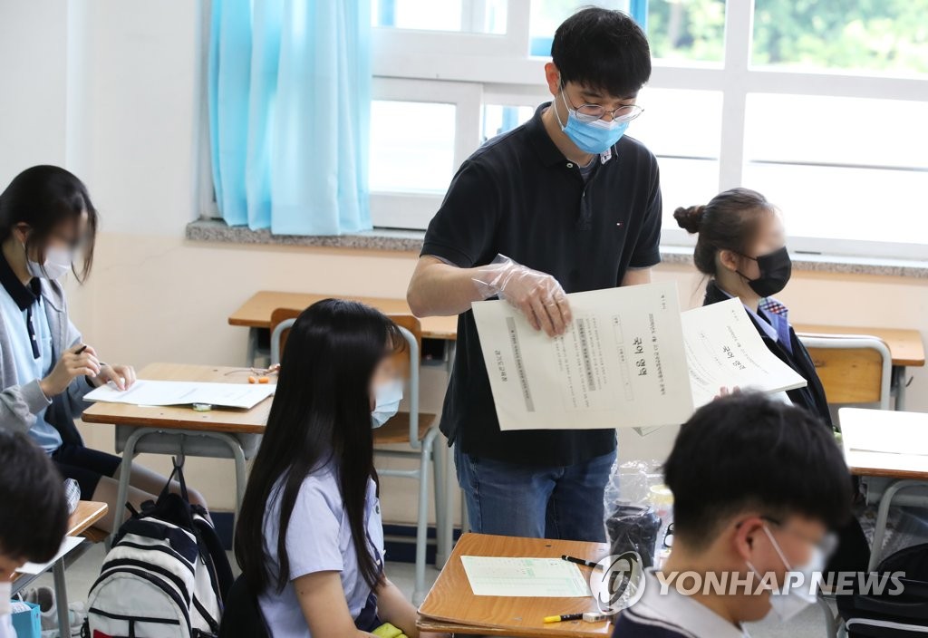 在京畿道水原市長安區棗園高中，教師戴著手套發放試卷。