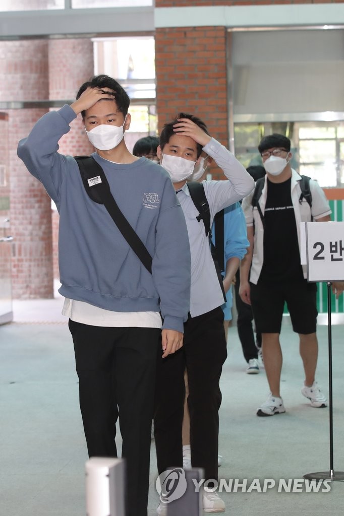 光州西區全南高中，學生們在進入教室前將額頭露出來，接受體溫檢測。
