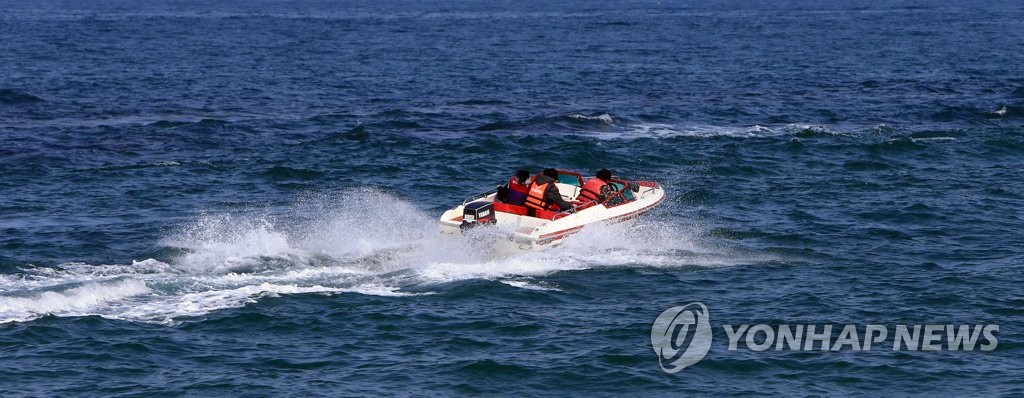 23日，在江原束草市束草海上，游客乘坐摩托艇掀起浪花，在海上奔馳。