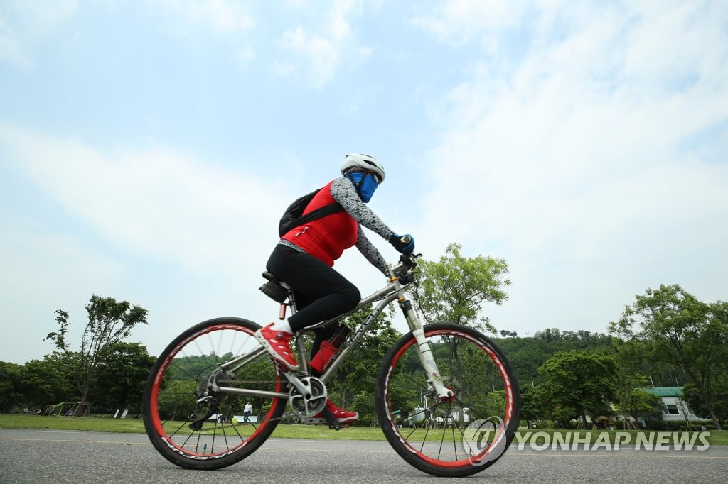 5月28日下午，一市民在首爾麻浦區漢江公園騎行。