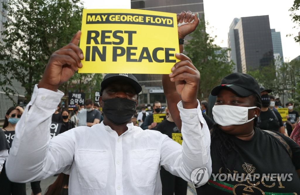 6月6日下午，在首尔明洞街头，两名在韩外国示威者手持标语以哀悼弗洛伊德。