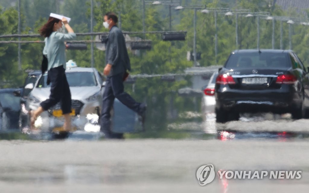 8日下午，首尔等地区拉响今夏首个酷暑天气警报，在首尔世宗大路，市民们地走过热气升腾的人行横道。