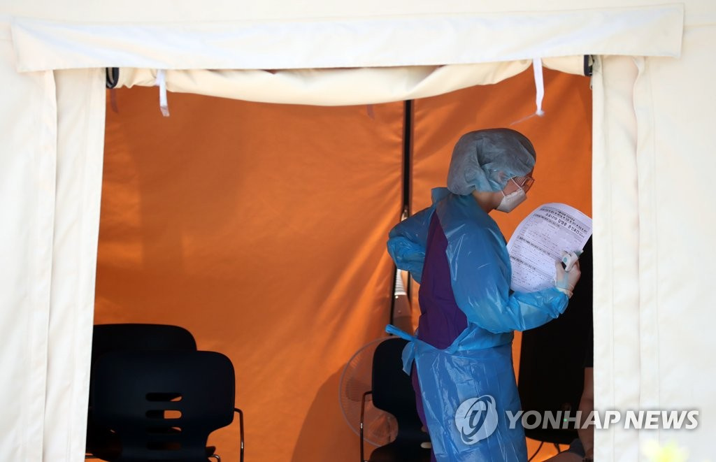 16日下午，在首爾中浪區醫療院篩查診療所內，醫務人員正在用一張問診單扇風散熱。