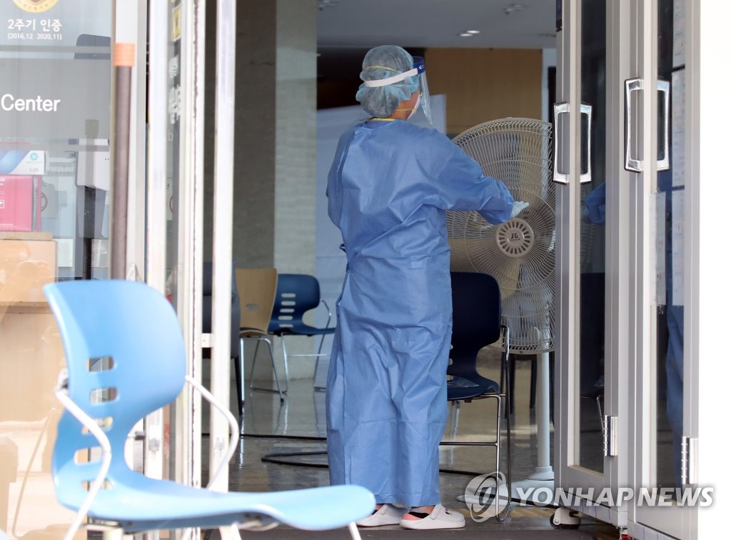 16日下午，在首爾中浪區醫療院篩查診療所內，醫務人員正在對著風扇降溫。