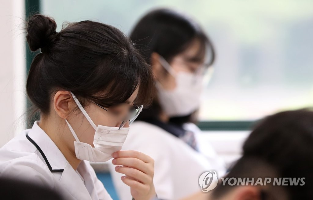 18日上午，在江原春川市江原大學師范學院附屬高中，學生們戴著口罩，正在准備高考模擬考試。