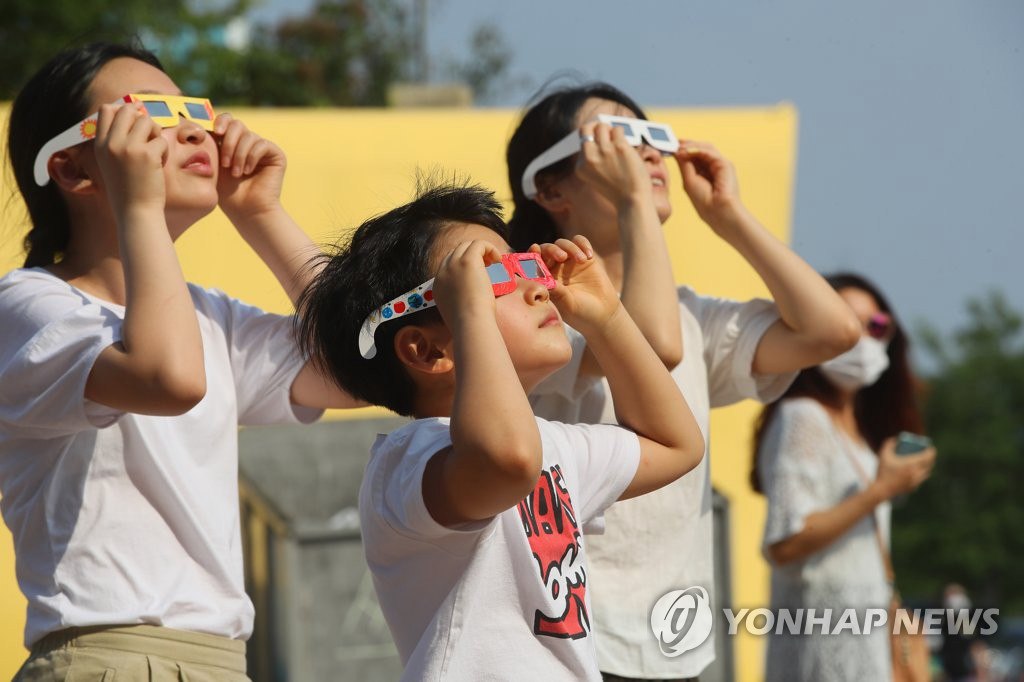 6月21日下午，市民們佩戴護目鏡，在首爾汝矣島漢江公園觀察日偏食。