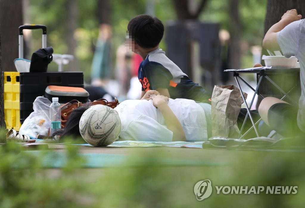 6月28日下午，在首爾市城東區首爾林，家長帶著孩子盡情玩耍后，正躺在地上的防潮墊上休息。