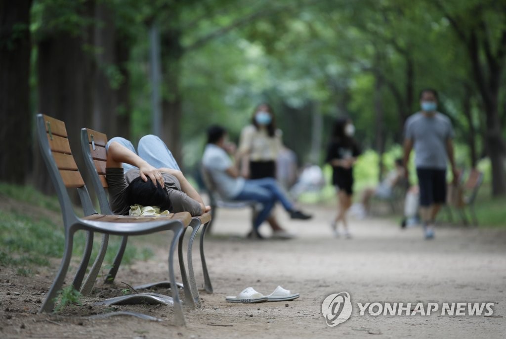 6月28日下午，在首爾市城東區首爾林，一名市民躺在公園長椅上休息。
