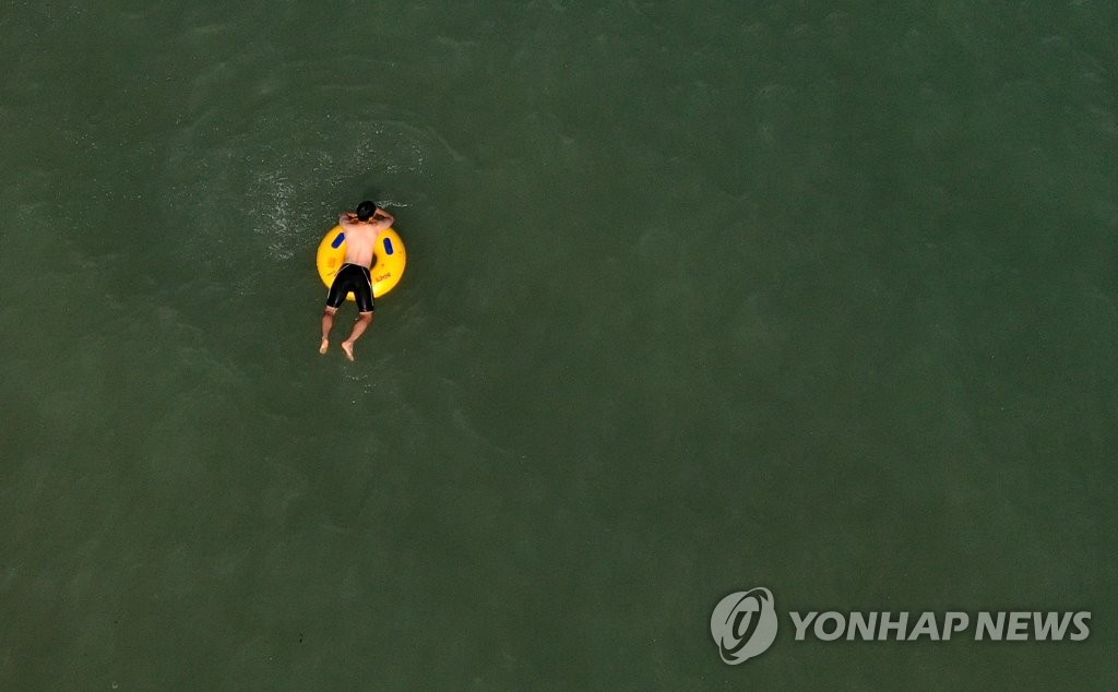 在釜山廣岸裡海水浴場，避暑游客正在悠閑自在地戲水。