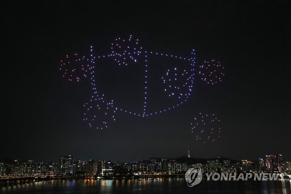 7月4日晚，韓國國土交通部在首爾永登浦區汝矣島漢江公園上空舉行了“無人機快閃秀”活動中，400多架無人機形象地展示出口罩的模樣。