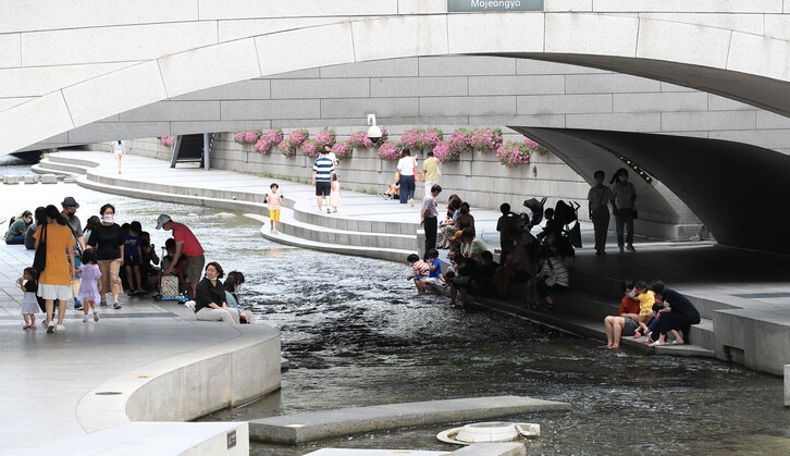 7月4日，酷熱來襲，在首爾清溪川，市民們紛紛坐在溪邊的台階上避暑納涼。