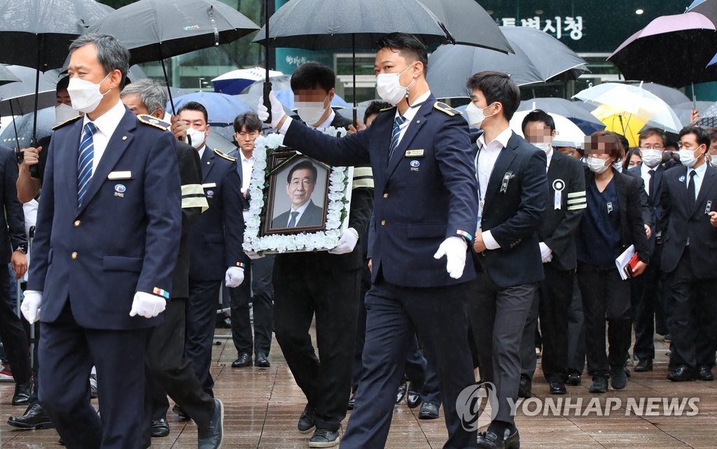 遗体告别仪式结束后，朴元淳遗属捧着已故首尔市长朴元淳遗像，走出首尔市政府大楼。