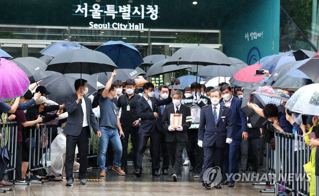 遗体告别仪式结束后，朴元淳遗属捧着已故首尔市长朴元淳遗像，走出首尔市政府大楼。
