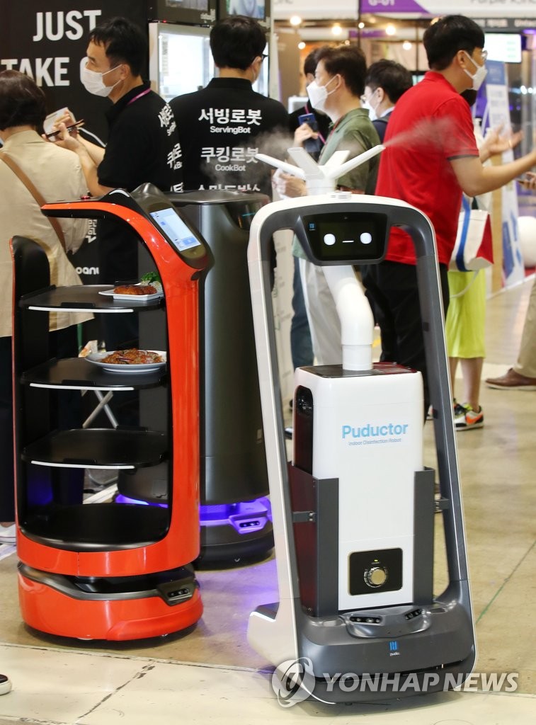 在“2020酒店秀”活動現場，企業正在演示防疫機器人（右）和機器人“服務生”。
