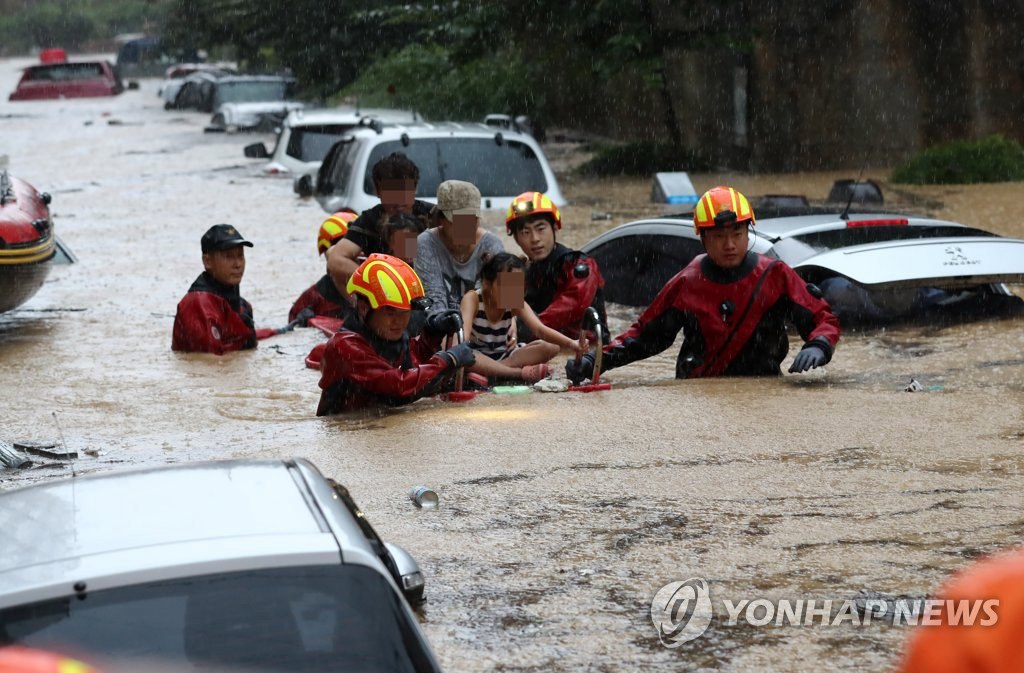 7月30日，在忠清南道大田市西区正林洞，消防队员在暴雨中开展救援工作，救出被困居民。