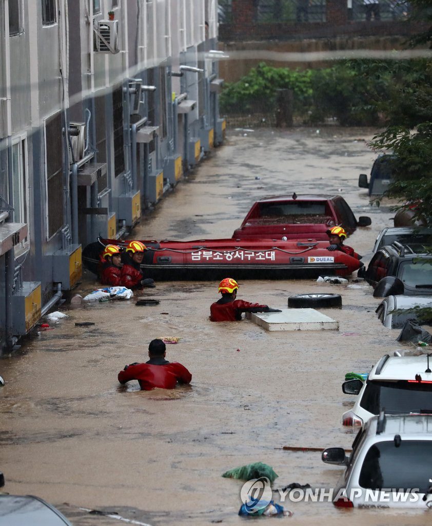 7月30日，在忠清南道大田市西区正林洞，停车场和部分建筑物被淹，消防队员正在开展紧急救援活动。