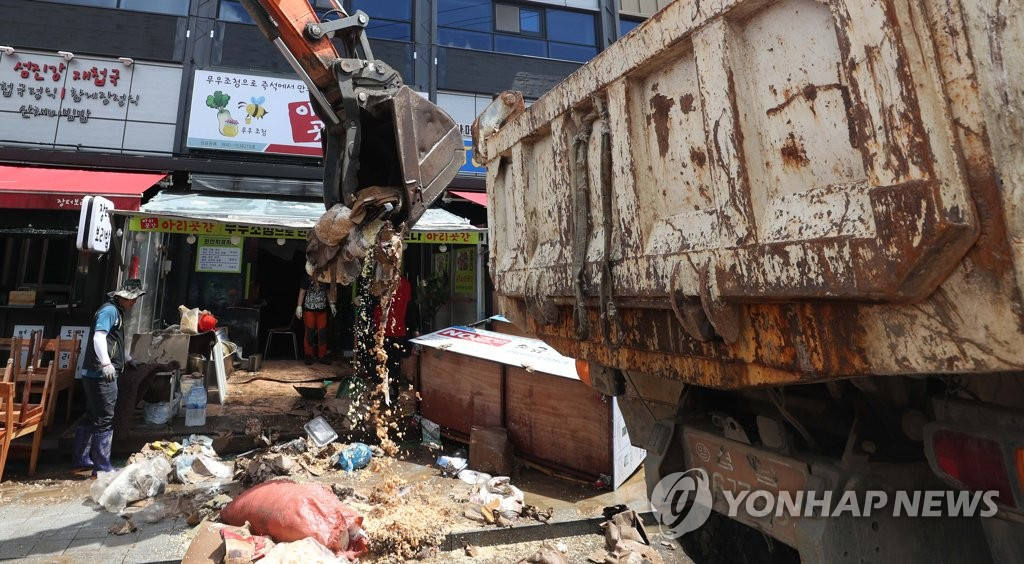 8月9日，場內負責人與正在利用挖掘機等重型裝備清理受災物品。
