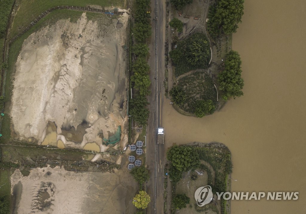 8月12日上午，在韓國首爾江東區漢江公園，工作人員正使用卡車清理由於強降水覆蓋在公園道路上的淤泥。