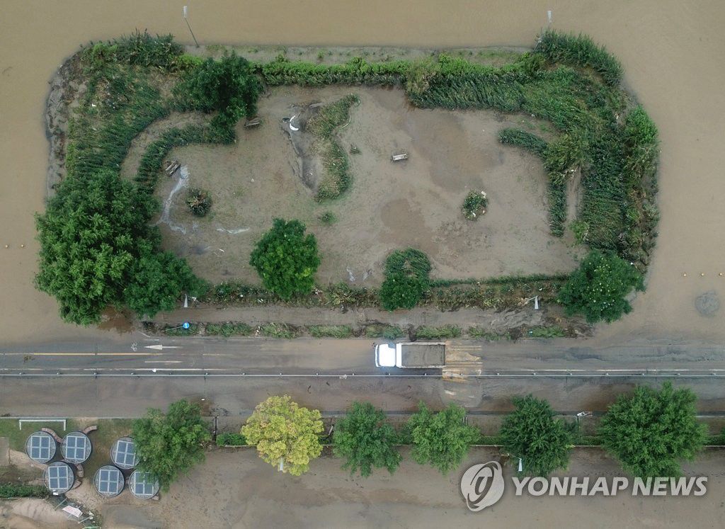 8月12日，在韓國首爾江東區漢江公園，工作人員正使用卡車清理由於強降水覆蓋在公園道路上的淤泥。