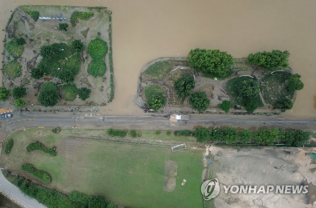 8月12日，在韓國首爾江東區漢江公園，工作人員正使用卡車清理由於強降水覆蓋在公園道路上的淤泥。