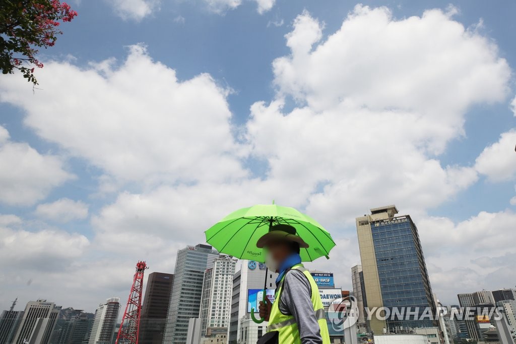 8月17日下午，“首爾路7017”步行街上的安保人員撐著遮陽傘工作。