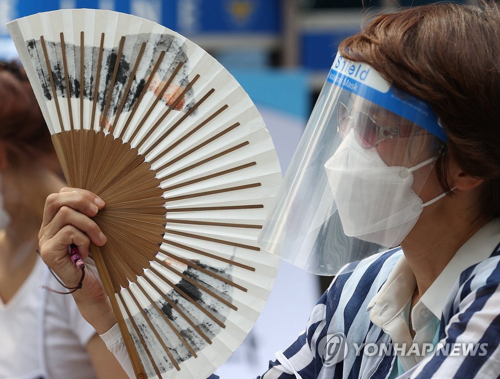8月17日下午，在首爾永登浦區，某市民參加一個大會時搖著扇子納涼。