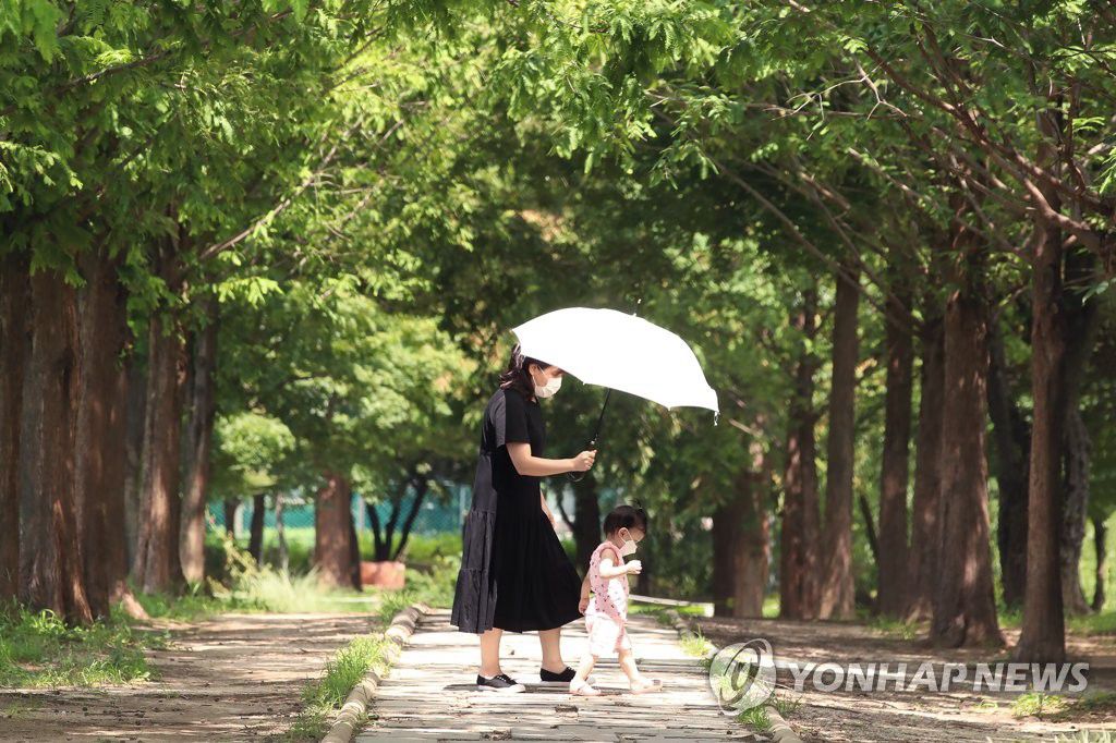 8月17日下午，在首爾城東區首爾林公園，一名媽媽為女兒撐傘遮陽。