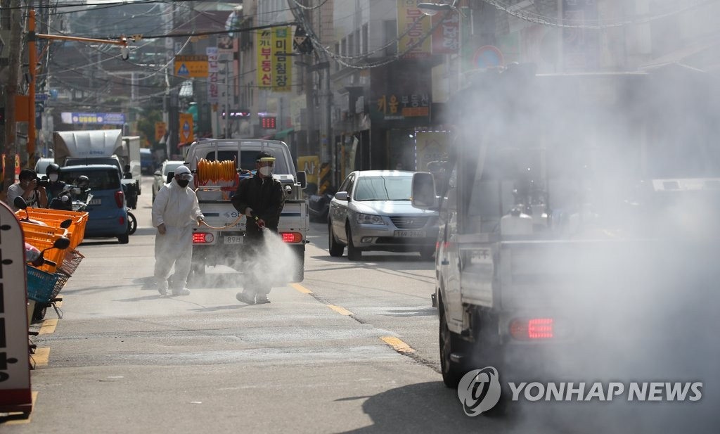 18日下午，在首爾城北區“愛第一教會”附近，商家、居民、公務員等正在街道上進行消毒作業。