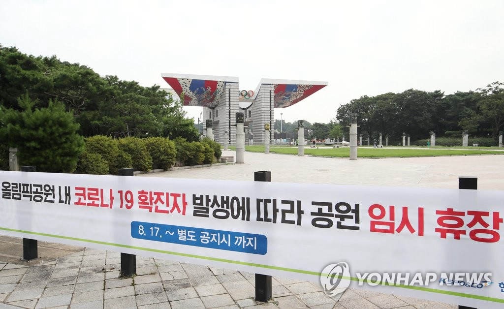 18日，首爾市鬆坡區奧林匹克公園入口處張貼臨時閉園的橫幅。自本月17日，園內一工作人員被確診感染新冠肺炎后，有關負責部門表示將閉園一周，嚴防疫情擴散。