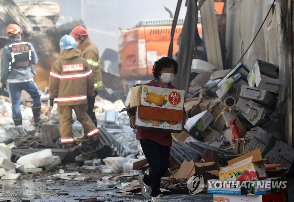 21日凌晨4時30分左右，首爾清涼裡農貿市場發生火災。聞訊趕來的商人正在往外搬運貨物。