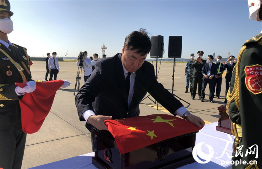 中国驻韩国大使邢海明为志愿军烈士棺椁覆盖国旗。 张悦 摄