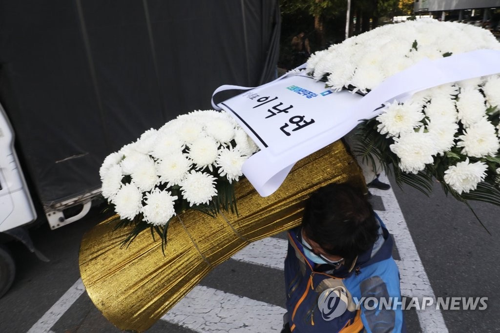 10月25日，韓國執政黨共同民主黨黨首李洛淵送來吊唁花圈，場地工作人員將其搬運至靈堂。