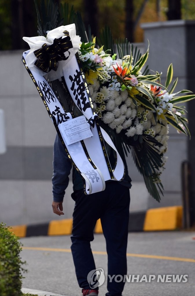 10月25日，韓國曉星集團會長趙顯俊送來吊唁花圈，場地工作人員將其搬運至靈堂。