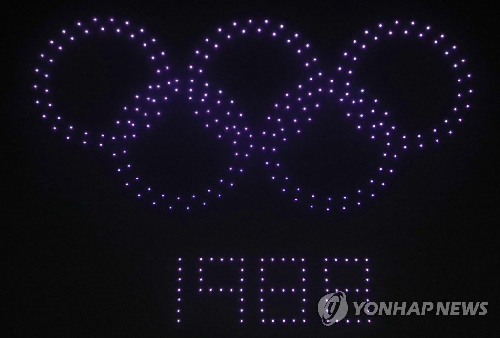 13日，首爾鬆坡區奧林匹克公園和平門上空，參展無人機擺出“奧運五環”造型。