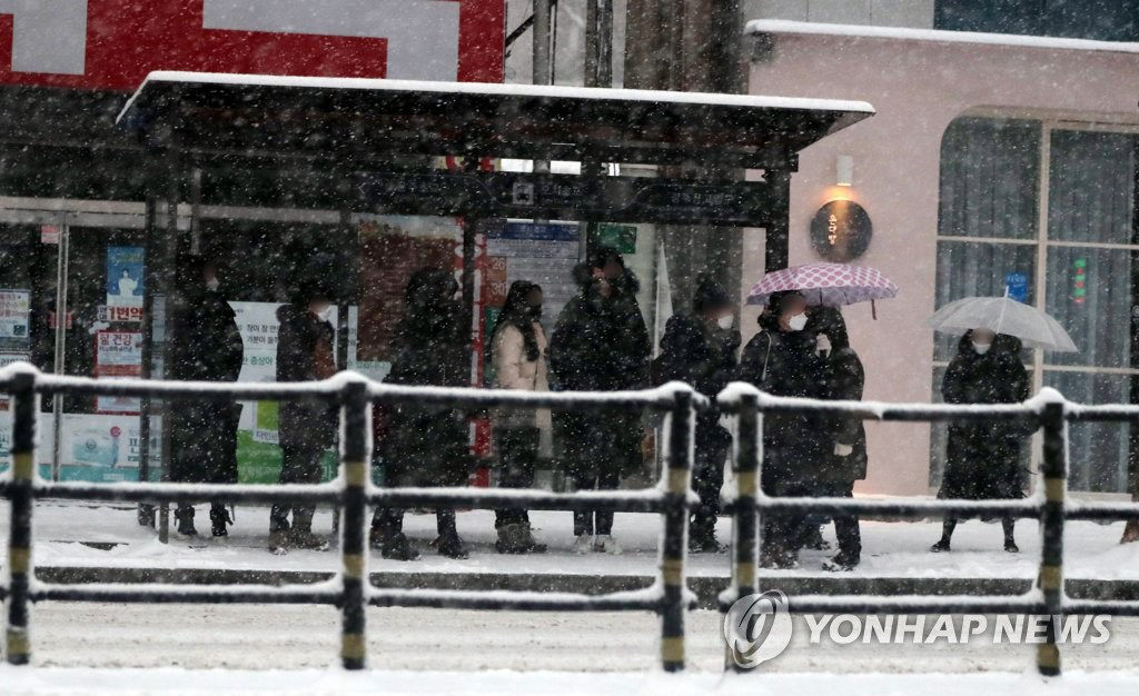 7日上午，在光州北區市中心，市民在暴雪中等待因惡劣天氣晚點的公交車。