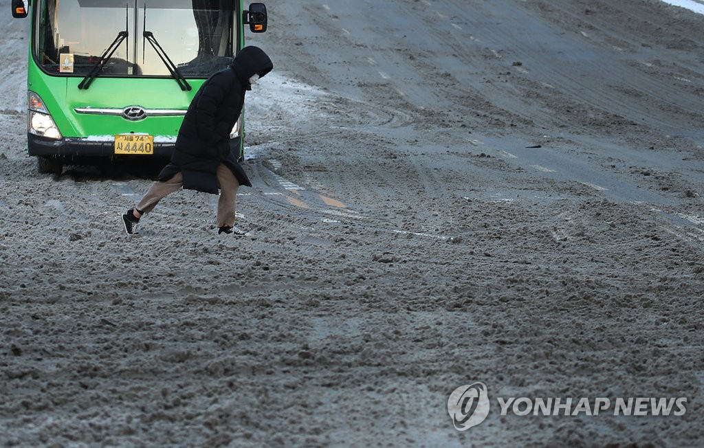 7日上午，在首爾江南區明洞大路上，一名市民正在走過被積雪覆蓋的人行橫道。